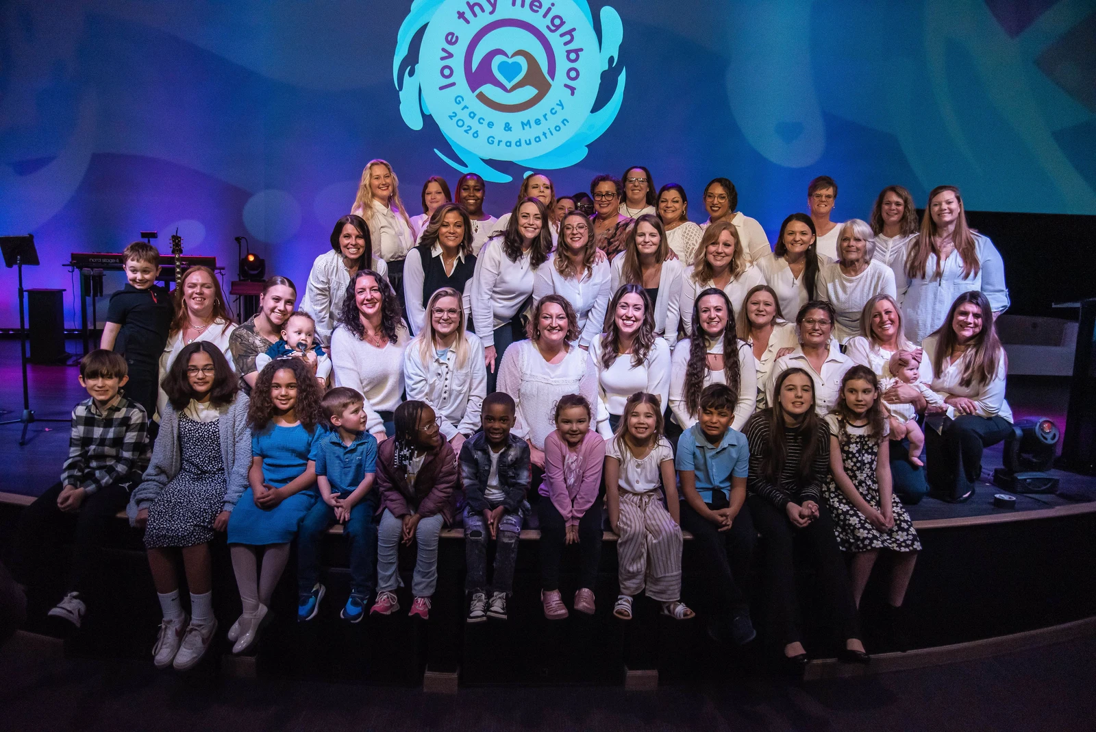 Grace & Mercy's 2026 graduation group gathered on stage with their families